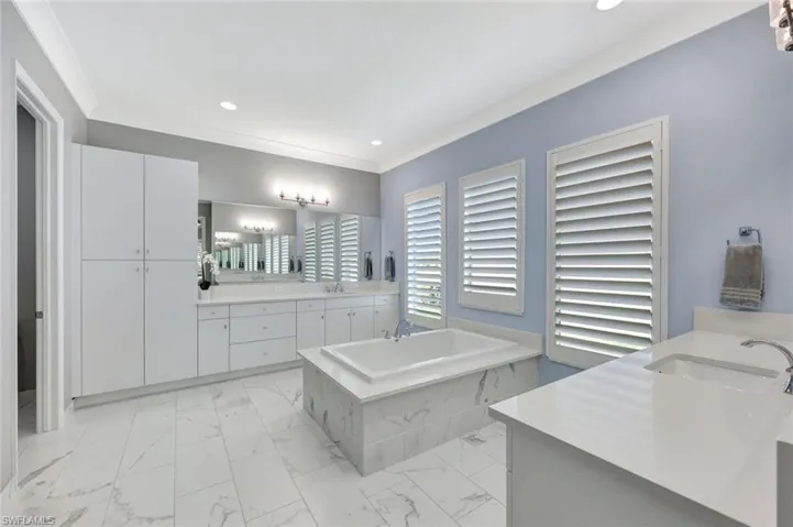 Bathroom featuring marble finish floor, two vanities, ornamental molding, and a sink