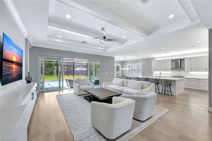 Living room featuring light wood-style flooring, a tray ceiling, and ceiling fan