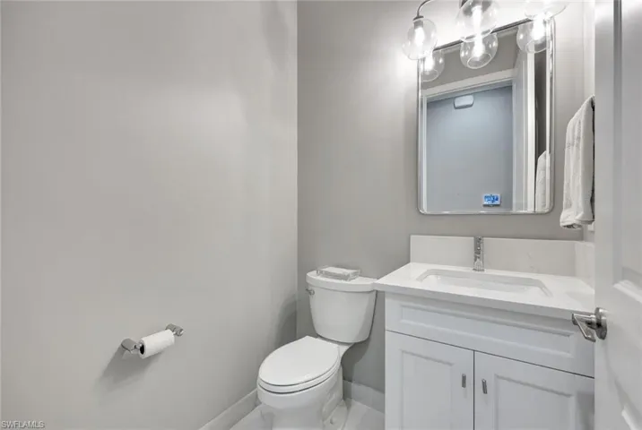 Bathroom featuring toilet, vanity, and baseboards