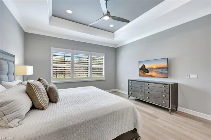 Bedroom featuring a raised ceiling, baseboards, and light wood-type flooring