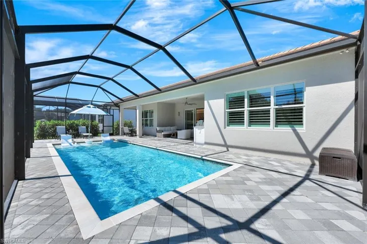 Outdoor pool featuring a ceiling fan, glass enclosure, and a patio area