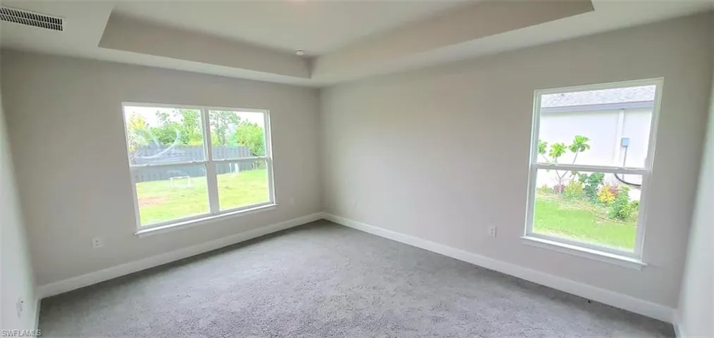 Primary Bedroom featuring carpet floors and a raised ceiling