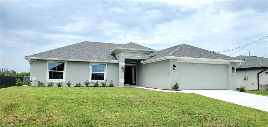 View of front of property with a garage and a front lawn