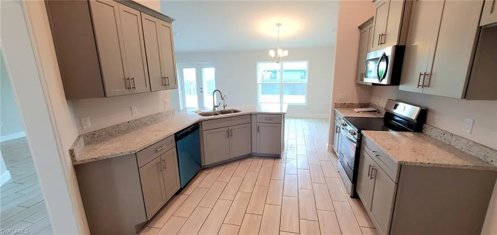 Kitchen featuring gray cabinetry, sink, appliances with stainless steel finishes, and decorative light fixtures