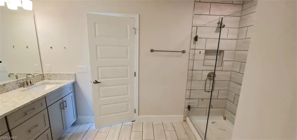 Primary Bathroom with a shower with shower door, vanity, and tile patterned flooring