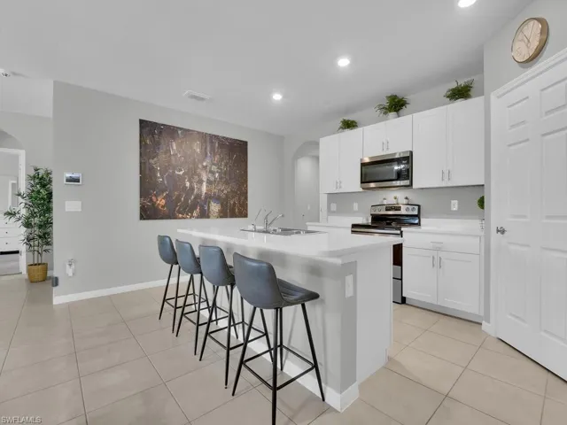 Kitchen with a sink, stainless steel appliances, arched walkways, and a center island with sink
