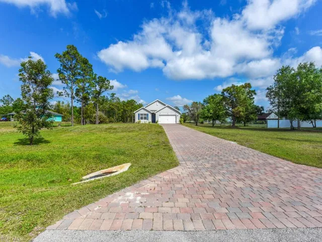 View of front of property with an attached garage, decorative driveway, and a front yard