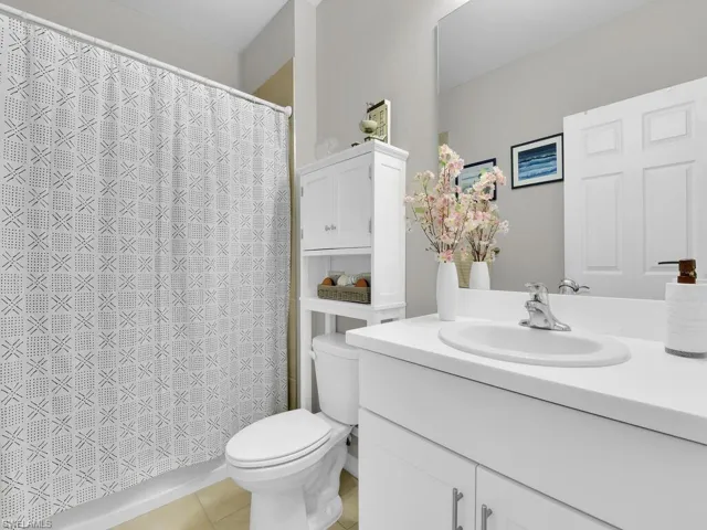 Bathroom featuring tile patterned floors, a shower with curtain, toilet, and vanity