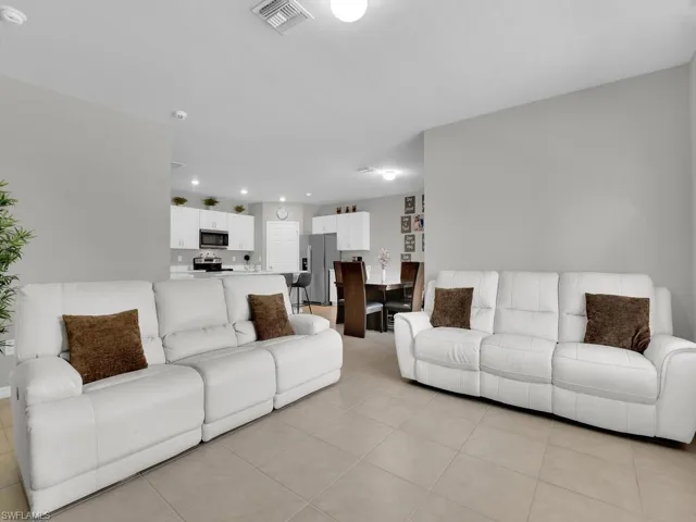 Living area with light tile patterned floors, visible vents, and recessed lighting