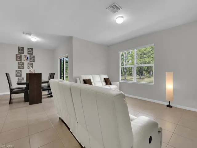 Living area featuring light tile patterned floors, visible vents, and baseboards