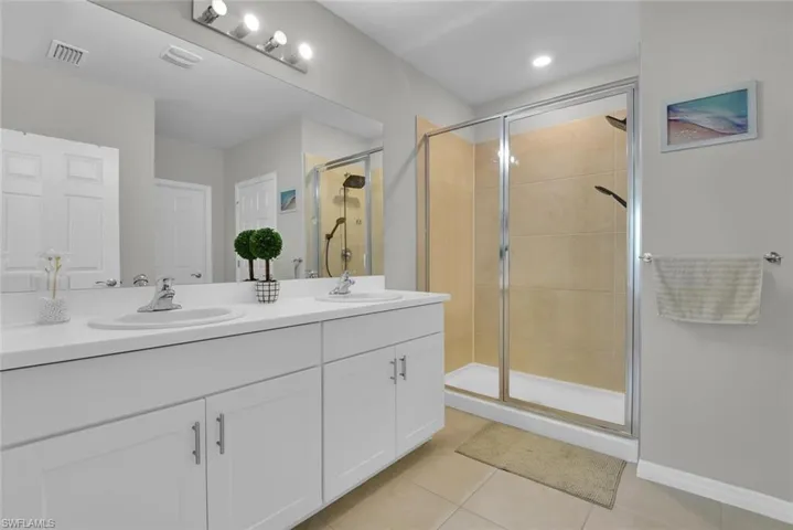 Bathroom featuring tile patterned flooring, visible vents, a shower stall, and a sink