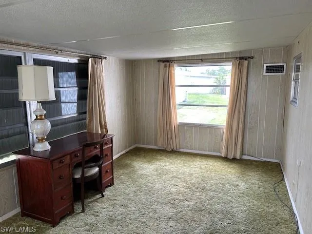 Carpeted office with a textured ceiling