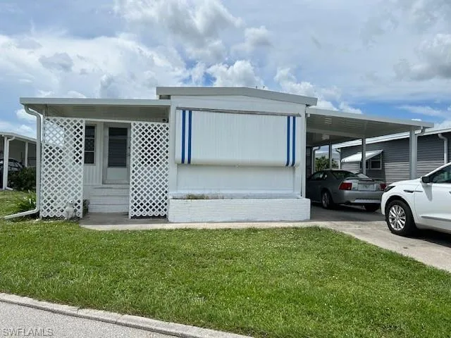 View of front of property with a carport, a front lawn, entry steps, and driveway