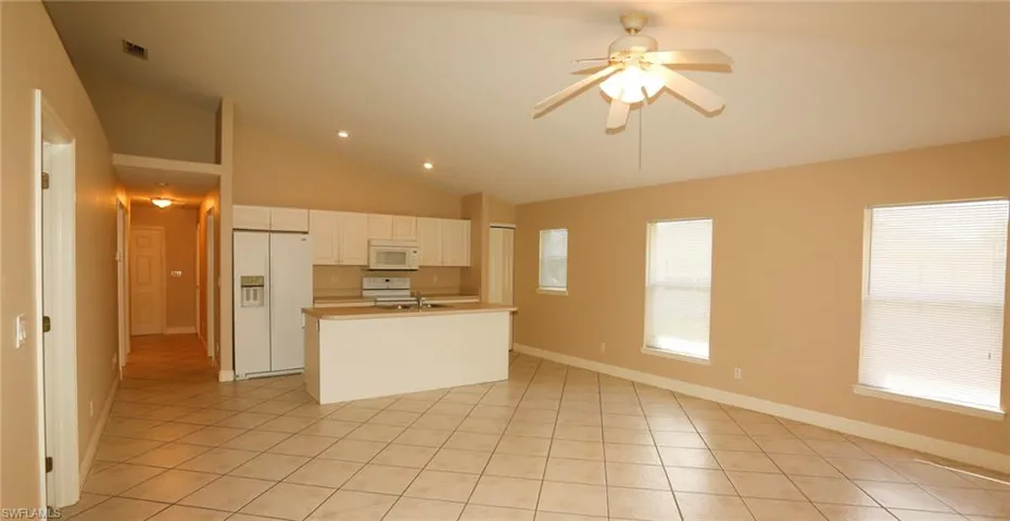 Open-concept living area featuring vaulted ceilings, diagonal tile flooring, and a ceiling fan