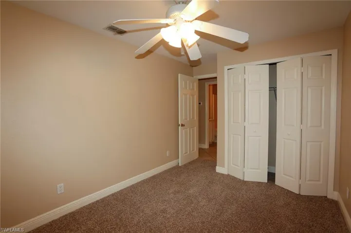 Interior room featuring neutral-toned walls, brown carpet flooring, and white baseboards