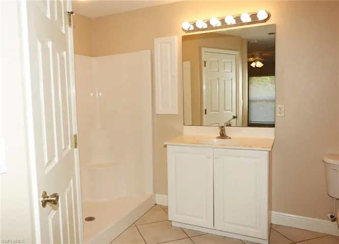 Bathroom featuring a white vanity with a light-colored countertop, an integrated sink, and a large mirror
