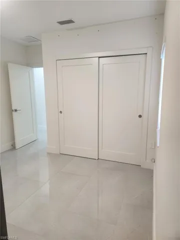 Unfurnished bedroom with light marble finish floors and a closet