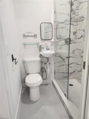 Bathroom with a marble finish shower and marble finish floors