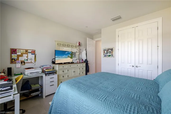 Bedroom with an office area, tile patterned flooring, and a closet