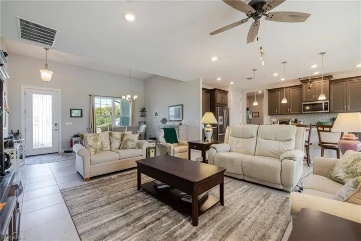 Living area with light tile patterned floors, a chandelier, a ceiling fan, and recessed lighting