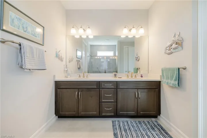 Full bathroom with double vanity, a stall shower, and light tile patterned floors
