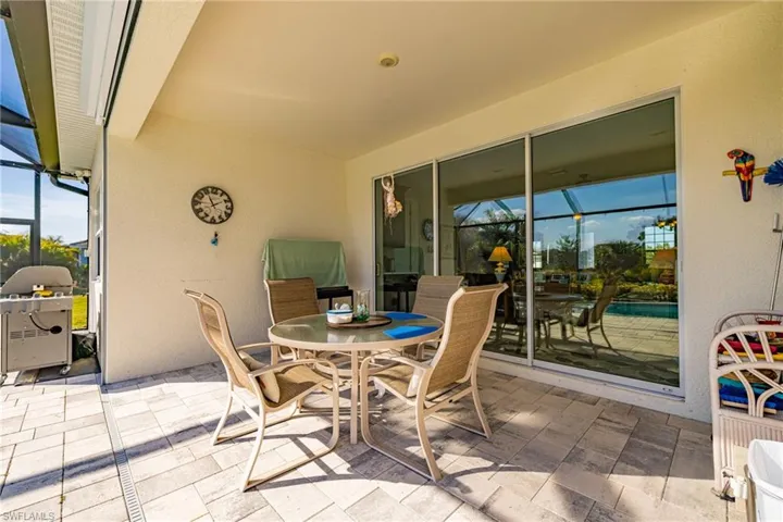 View of patio with glass enclosure, a sunroom, outdoor dining space, and grilling area