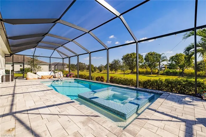 View of pool with a sunroom, glass enclosure, a pool with connected hot tub, and a patio area