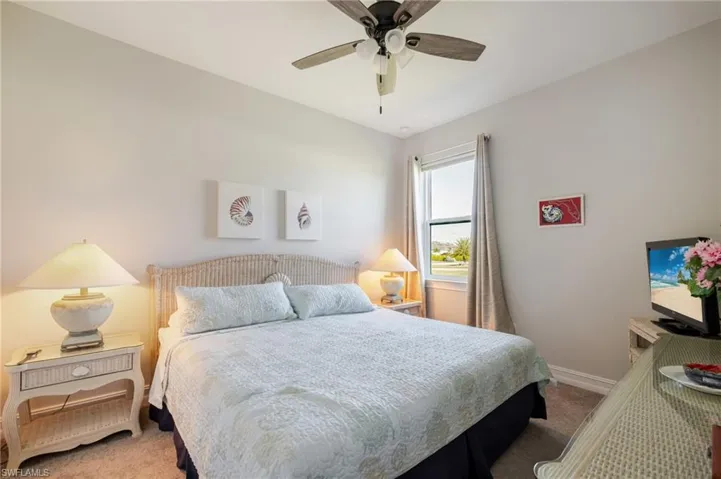 Carpeted bedroom with a ceiling fan and baseboards