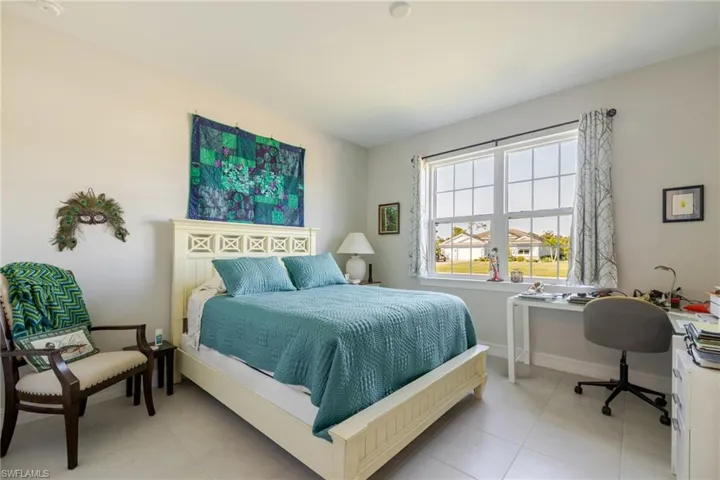 Bedroom with light tile patterned floors and an office area