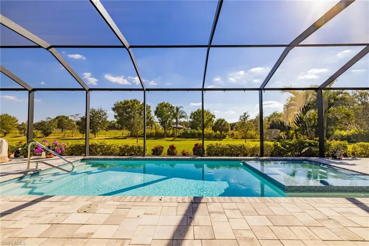 View of pool with glass enclosure, a pool with connected hot tub, and a sunroom