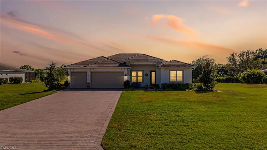 View of front of house featuring decorative driveway, a lawn, and stucco siding