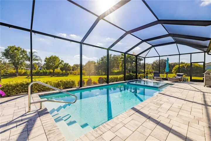 View of pool featuring a sunroom, glass enclosure, and a patio area