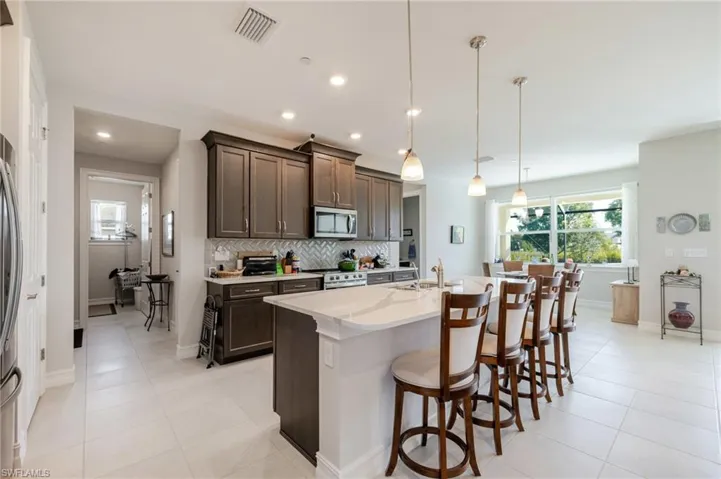 Kitchen with a breakfast bar, dark brown cabinetry, healthy amount of natural light, and a center island with sink
