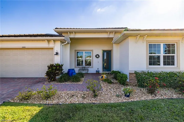 View of front of property featuring stucco siding, driveway, an attached garage, and a porch