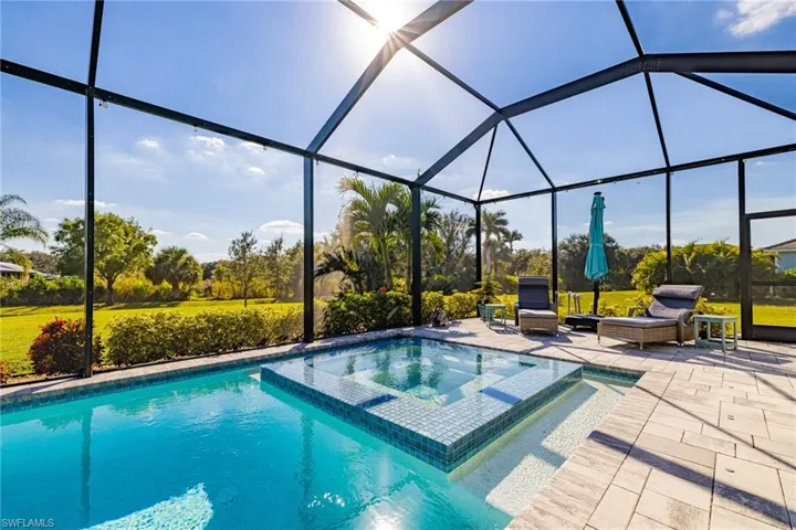 View of swimming pool featuring a lanai, a sunroom, a pool with connected hot tub, and a patio