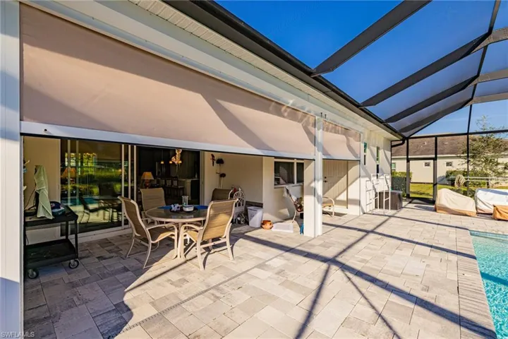 View of patio / terrace featuring a sunroom, glass enclosure, an outdoor pool, and outdoor dining area