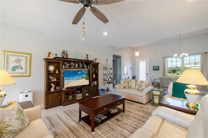 Living room with light tile patterned floors, ceiling fan, and a chandelier