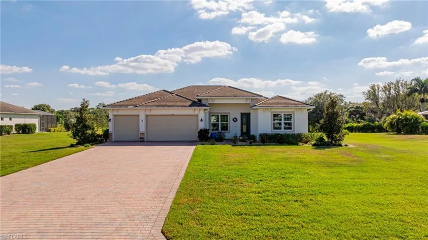 View of front facade with decorative driveway, an attached garage, and a front lawn