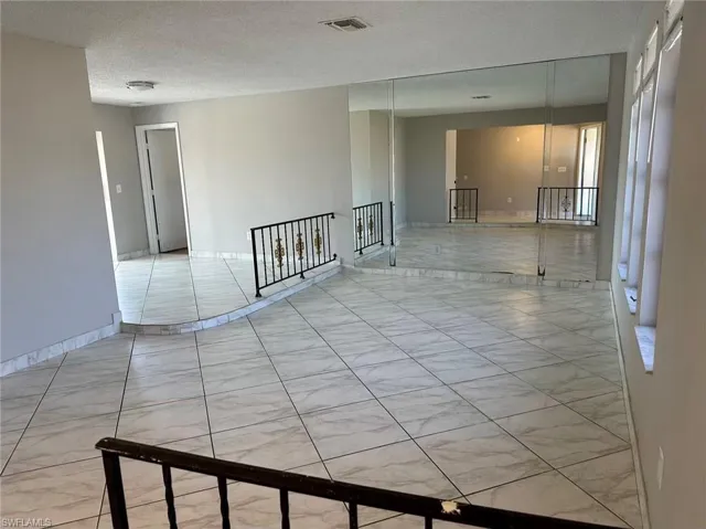 Empty room with a textured ceiling and baseboards