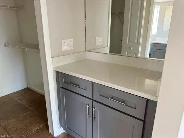 Bathroom featuring a spacious closet, vanity, and dark tile patterned flooring