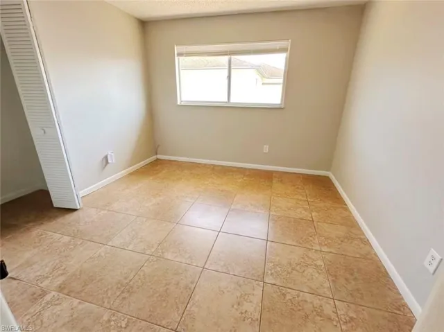Empty room with light tile patterned floors and a textured ceiling