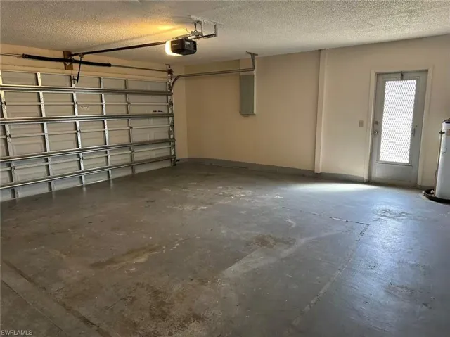 Garage featuring water heater, a garage door opener, and electric panel