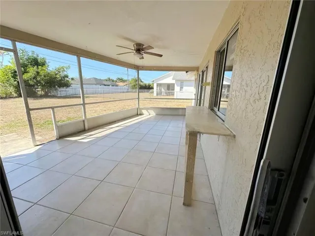 Unfurnished sunroom featuring ceiling fan and a residential view