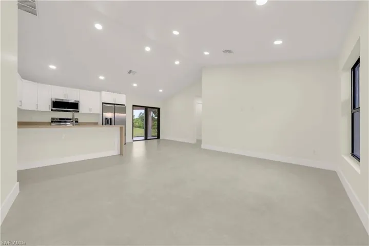 Unfurnished living room with recessed lighting, vaulted ceiling, concrete flooring, and french doors