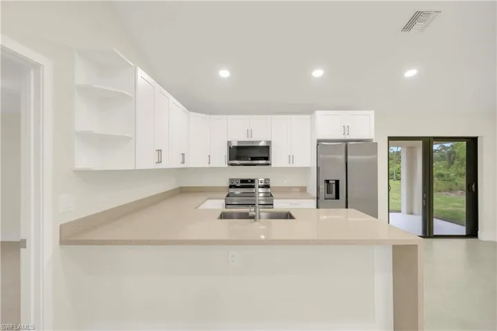 Kitchen featuring open shelves, white cabinetry, appliances with stainless steel finishes, a peninsula, and recessed lighting