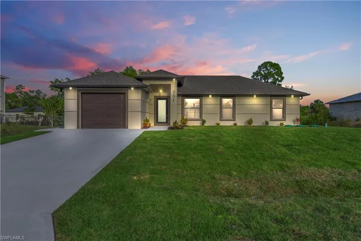 View of front of home featuring concrete driveway, stucco siding, a front lawn, and a shingled roof
