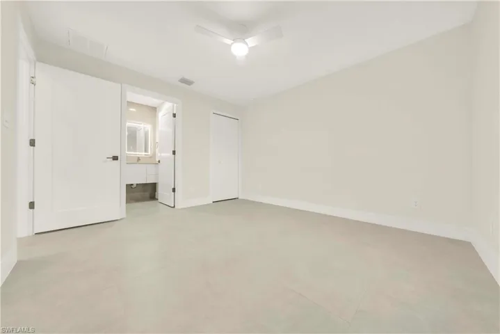 Unfurnished bedroom featuring a ceiling fan, a closet, and ensuite bathroom