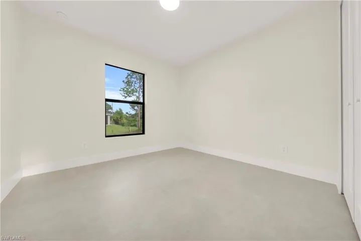Unfurnished room with baseboards and finished concrete flooring
