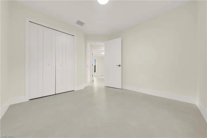 Unfurnished bedroom with finished concrete flooring and a closet