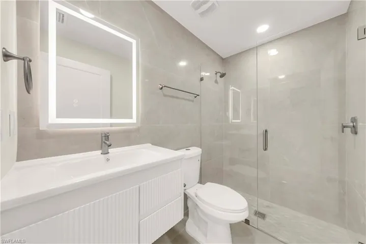 Full bathroom featuring tile walls, vanity, a stall shower, and recessed lighting